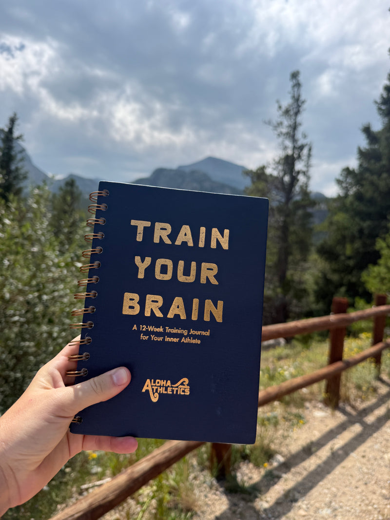 Guided journal for athletes held up with mountains in the background